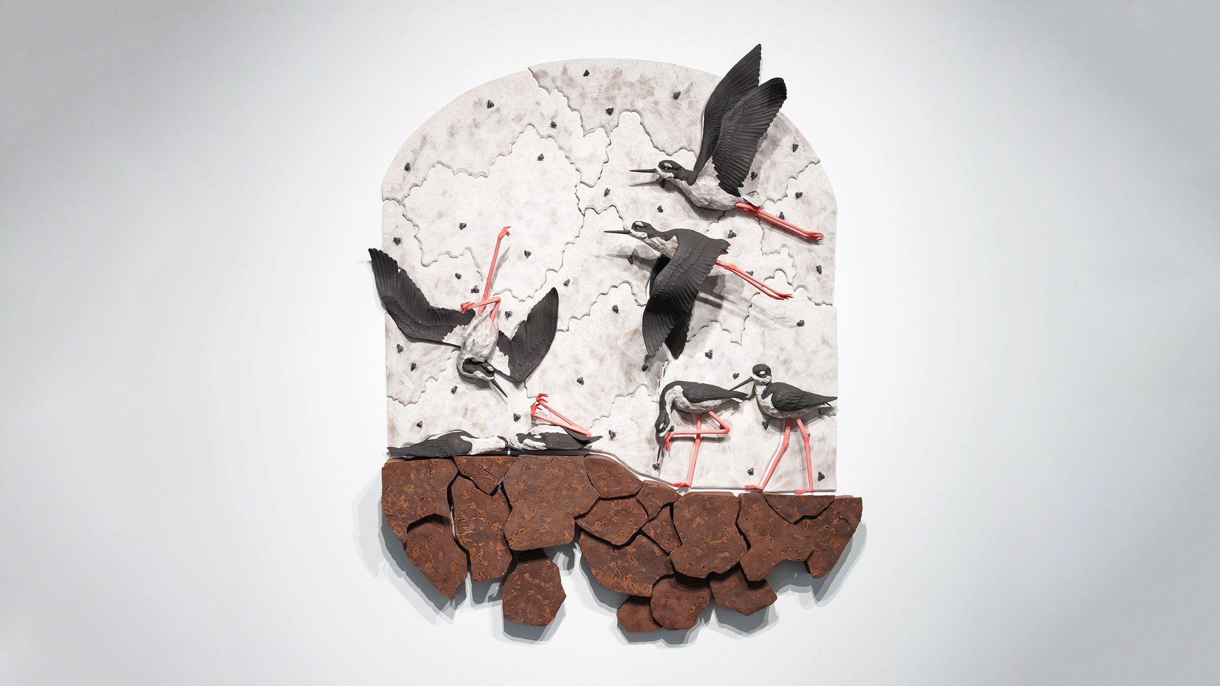 A life-size sculpture of Black-necked Stilts in a cracked, dried up landscape.