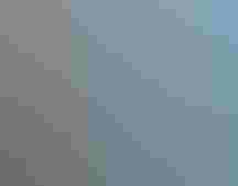 A kayaker paddles in a pristine lake, the clear water mirroring the forest on either side.