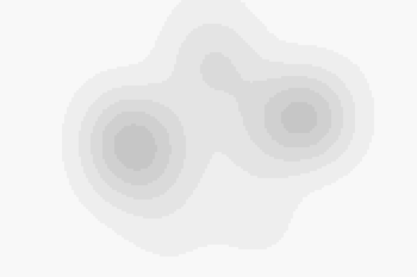 A pair of Red-crowned Cranes stand breast-to-breast in the snow, sinuous black necks nearly intertwined. Their black-tipped wings and black legs stand out against their white bodies and a completely white background.