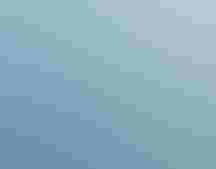 People in a raft float by penguins atop a glacier.