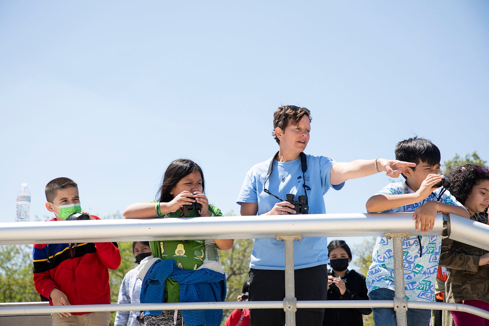 person with binoculars points off-camera