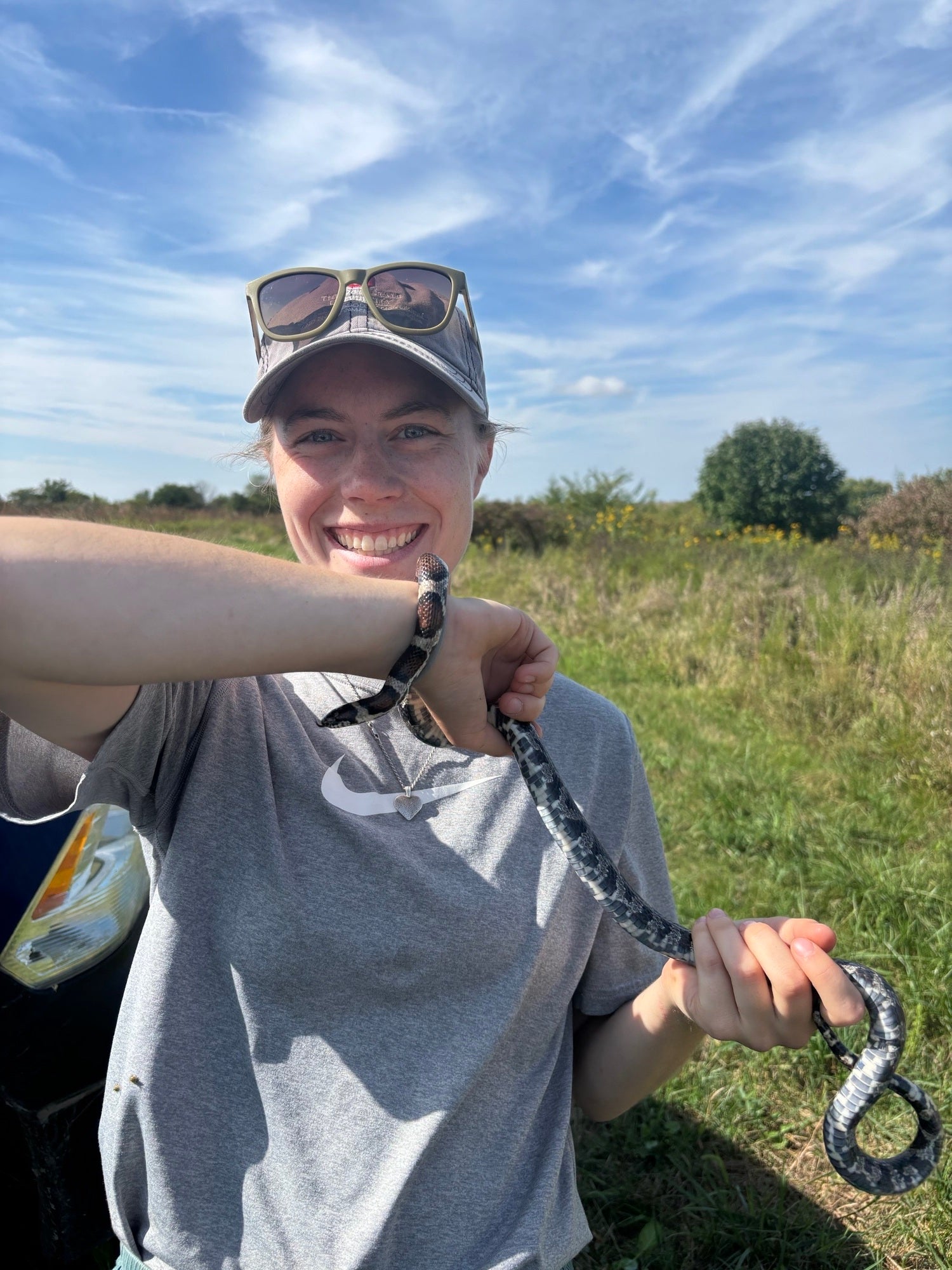 A woman holds a snake in a field