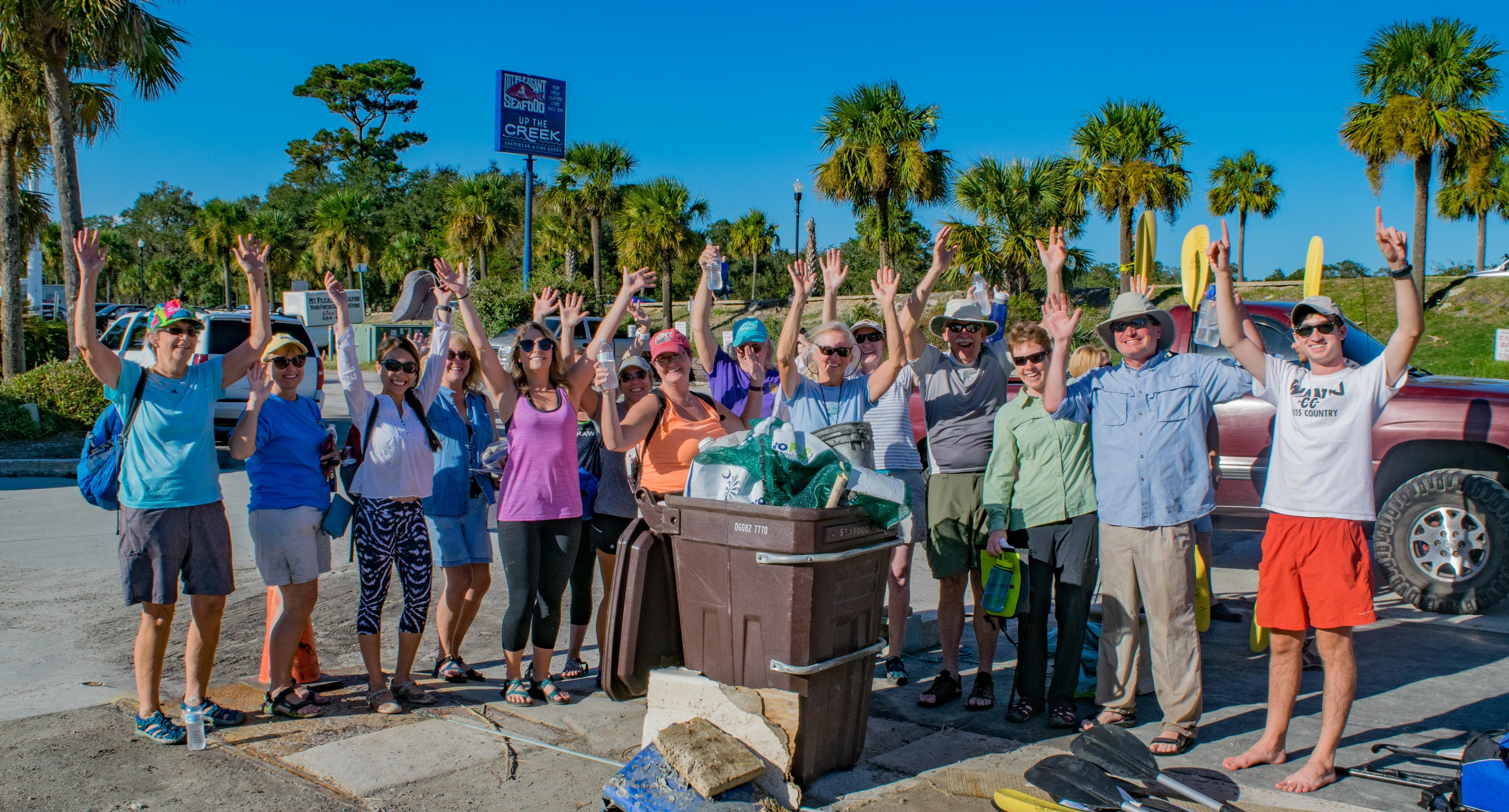 A group of volunteers standing in front of a pile of trash that was collected on the beach