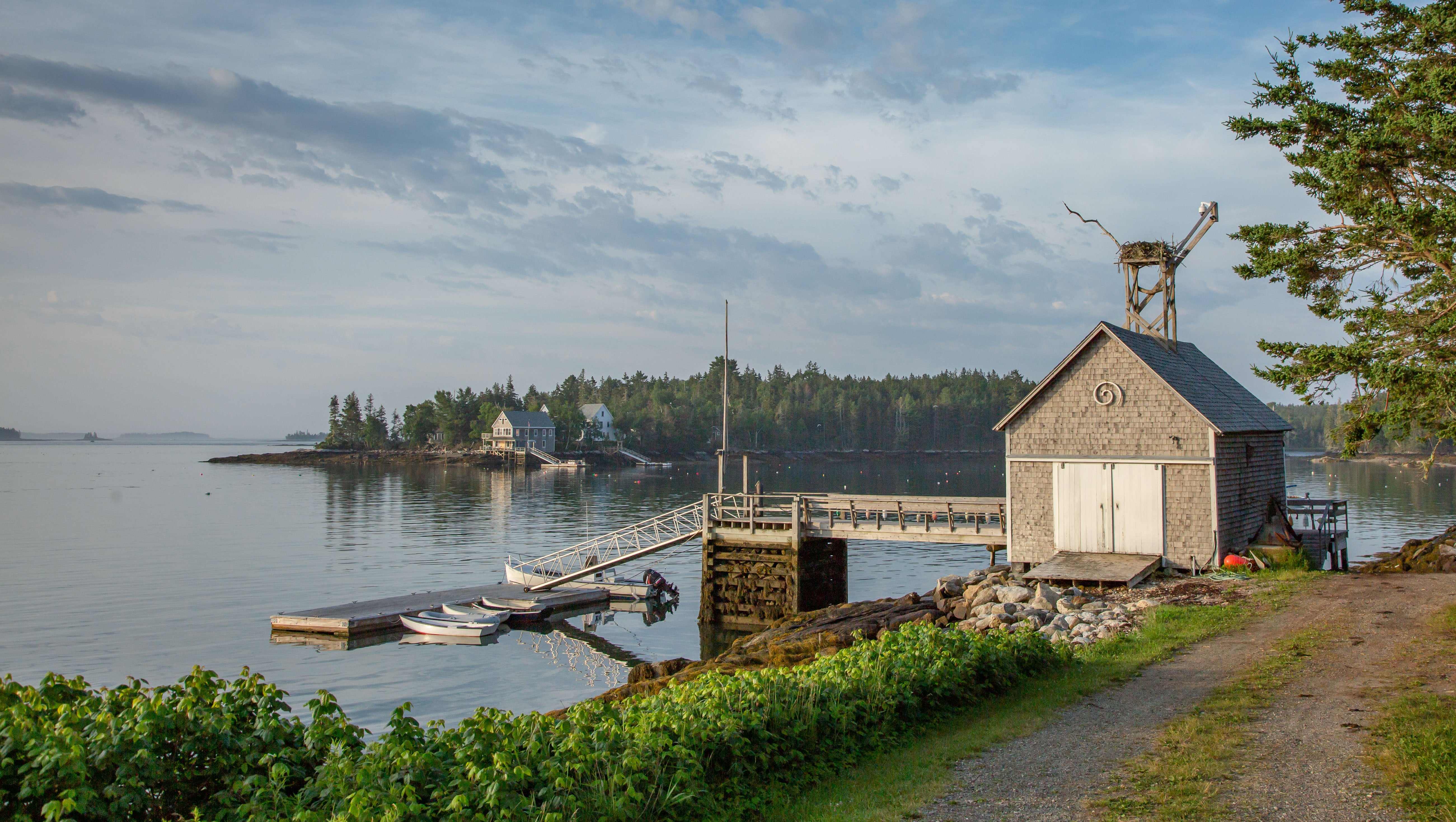 A boathouse and dock with small boats moored in the water. 