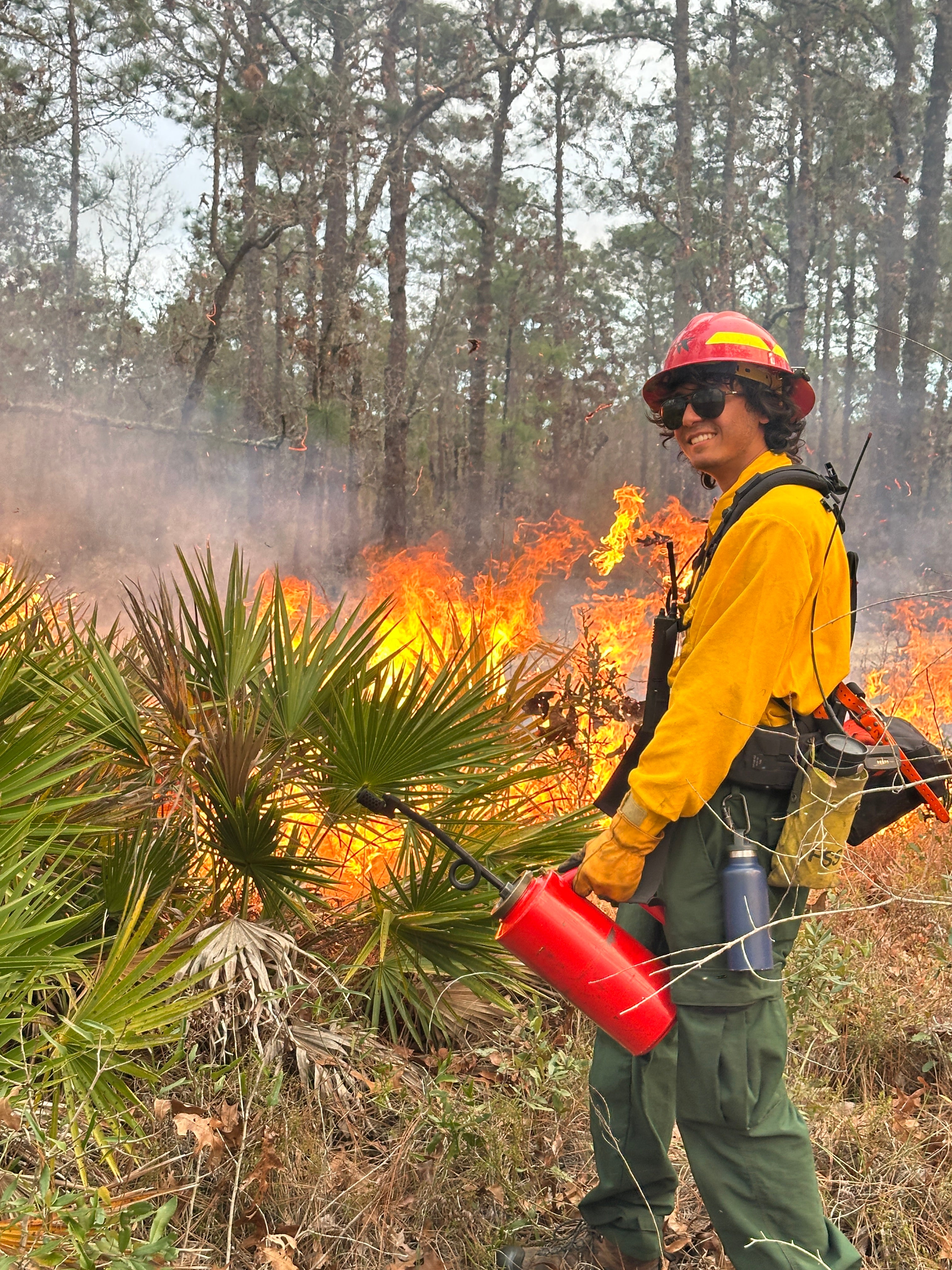 A man wearing yellow holding a drip torch