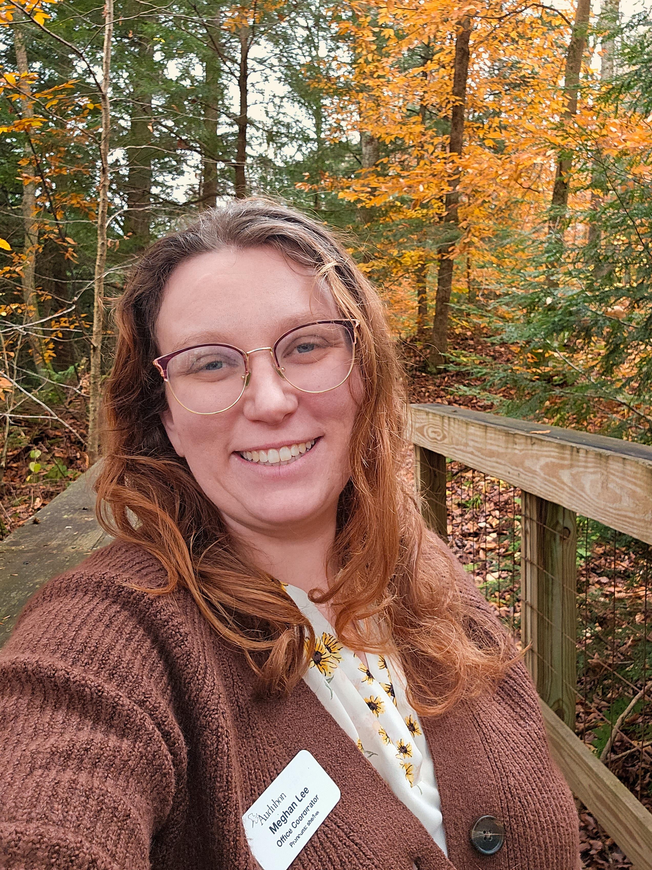 A photo of Meghan Lee-Hall standing in the woods in fall.