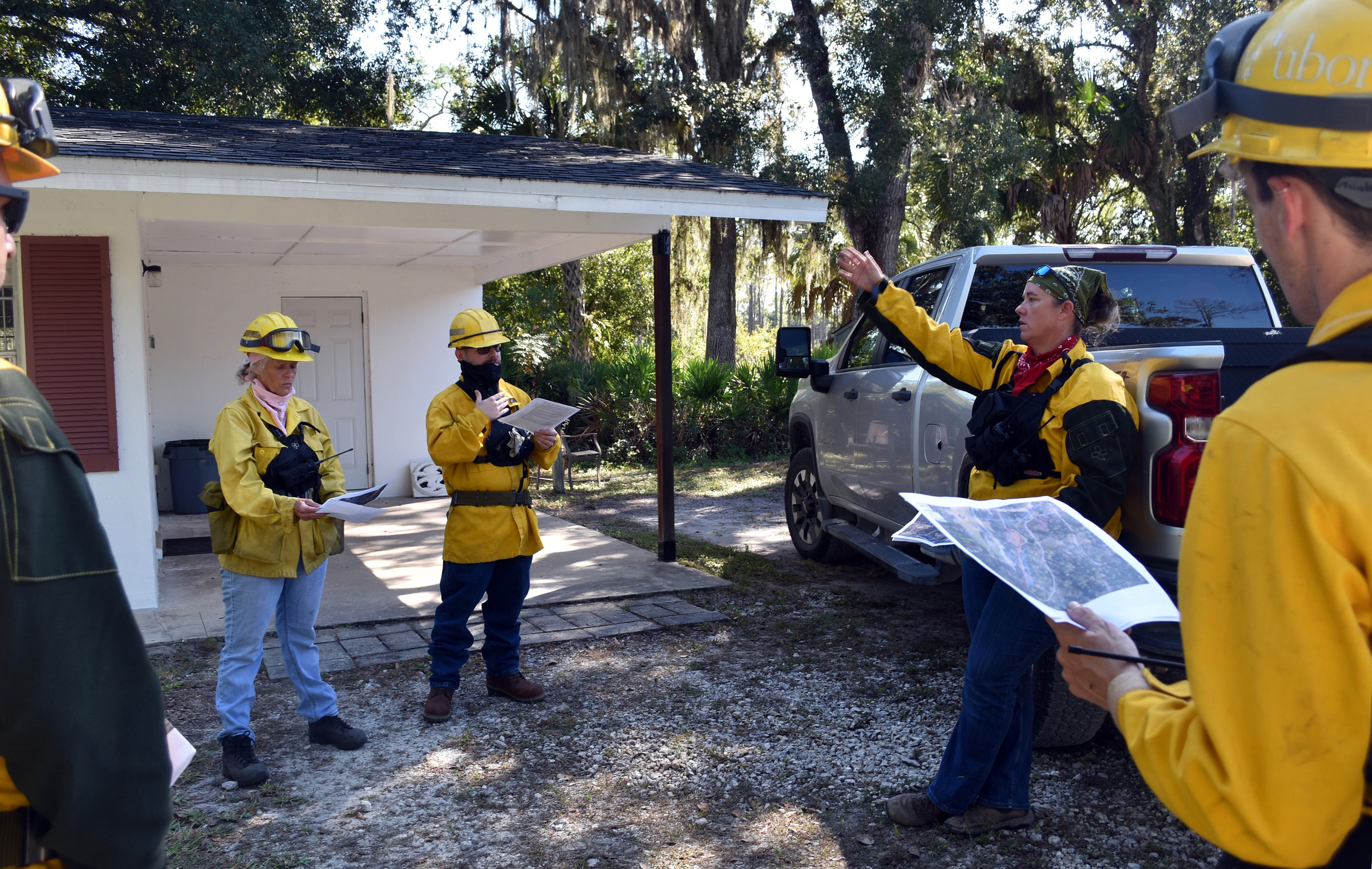 People wearing yellow jackets stand in a group near a building