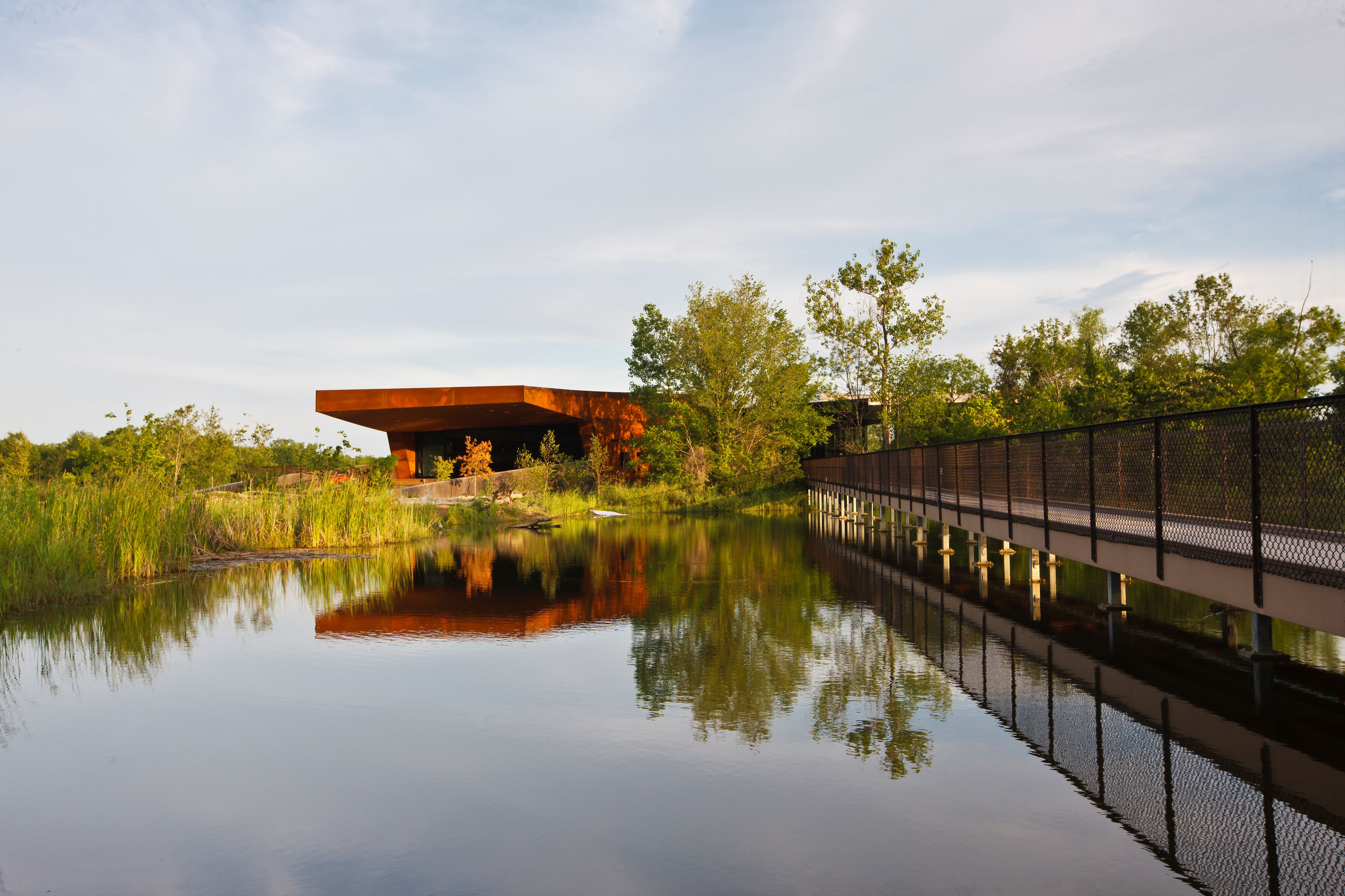Boardwalk bridge over water leading to a building in the distance