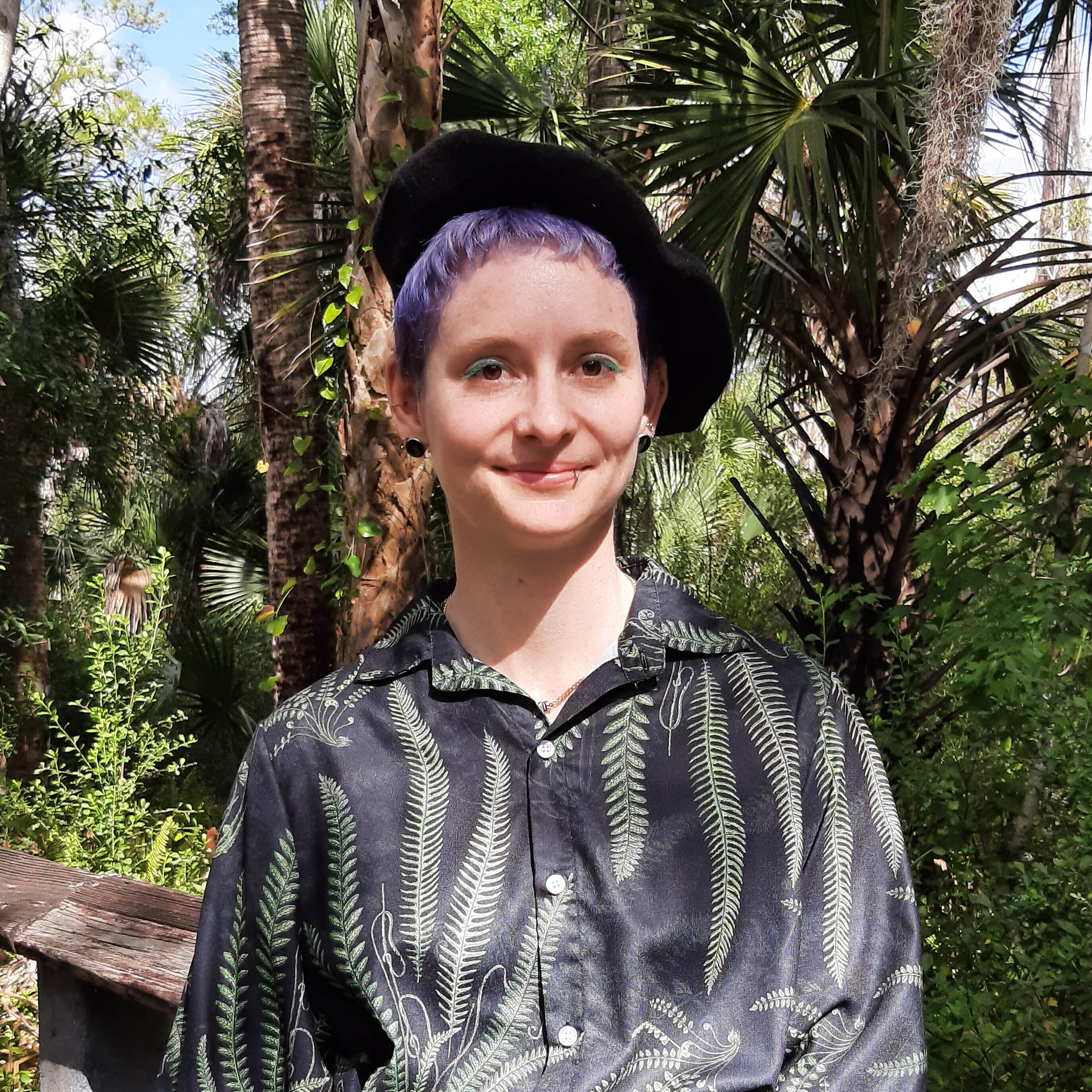 A smiling woman standing on a boardwalk through a forest.