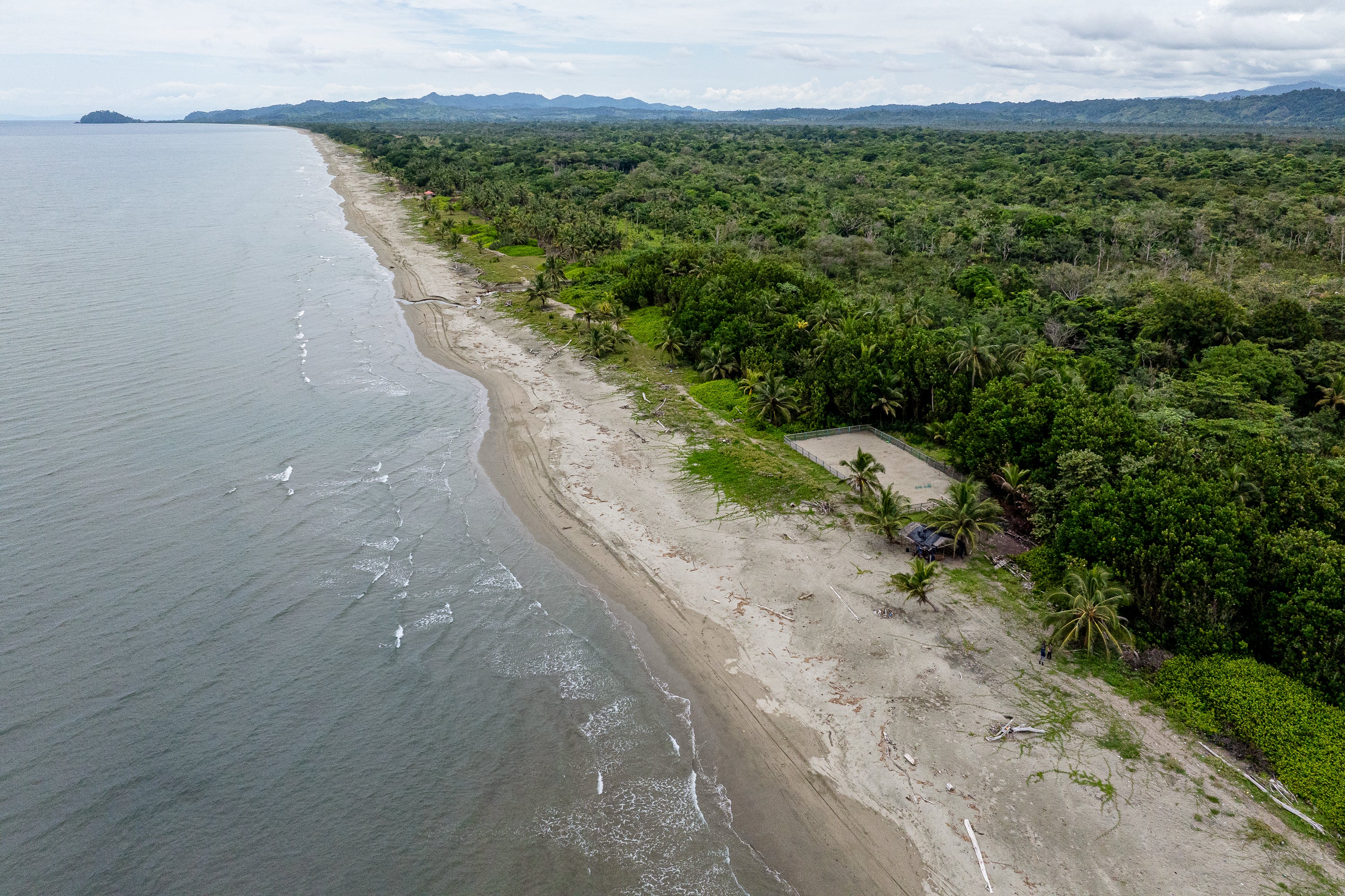 An aerial view of a lush, jungle-side beach in the Darien Gap. 