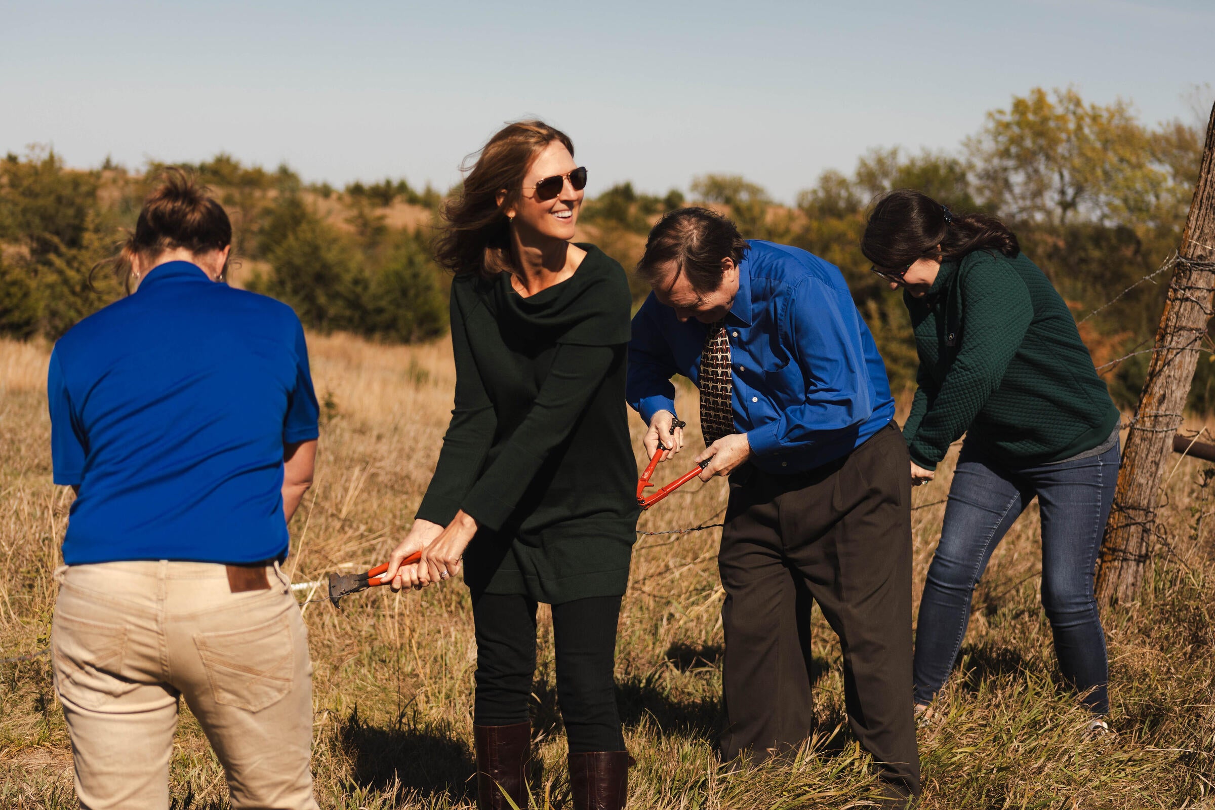four people outside cutting a fence