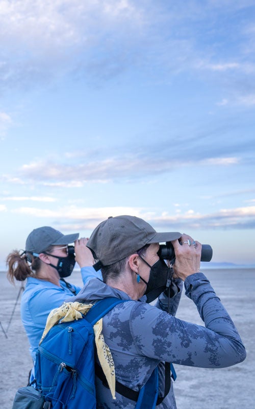 Two people look through binoculars.