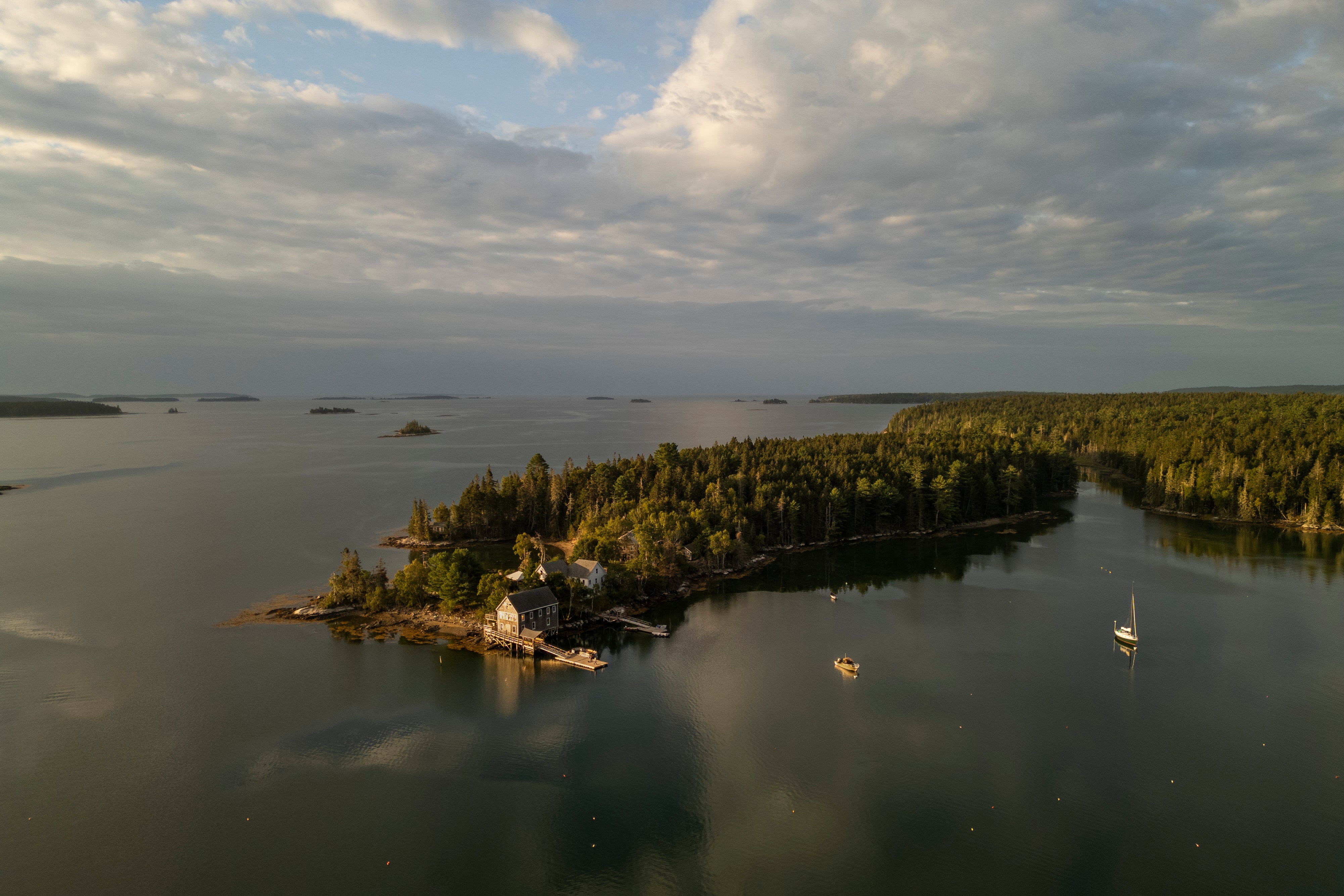 The arial view of an island with a building perched along the shoreline and small islands in the distance. 