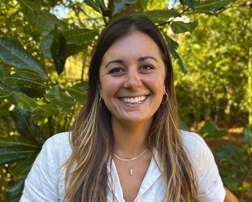 A woman with long brown hair in a white collared shirt