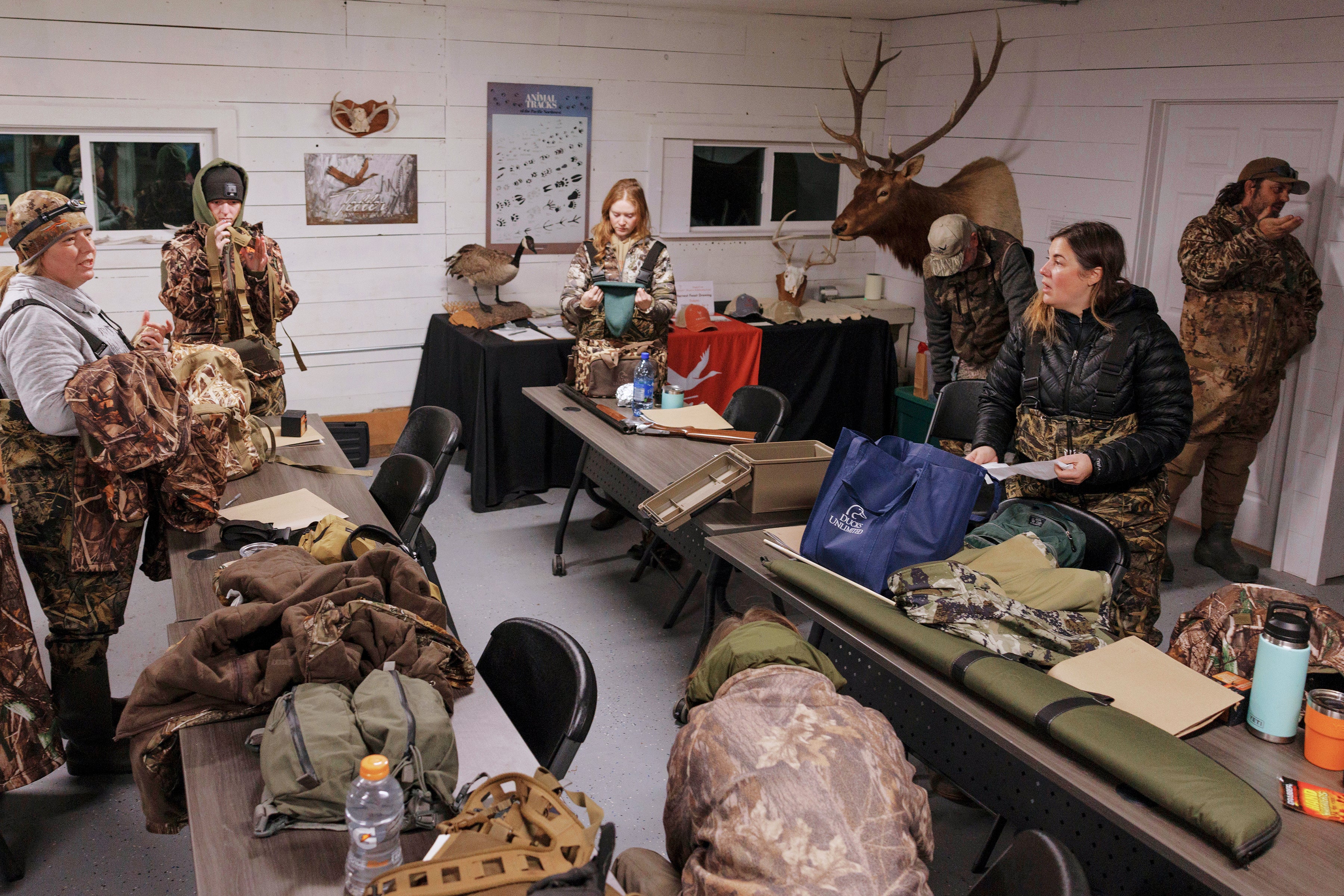 A group of women put on camouflage waders in a meeting room.
