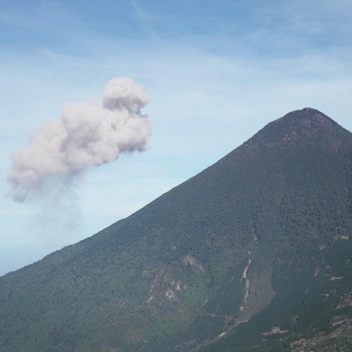 A cloud of ash and steam rises from Guatemala's Santiaguito volcano (hidden behind the cone-shaped Santa Maria volcano in front). Noah Strycker