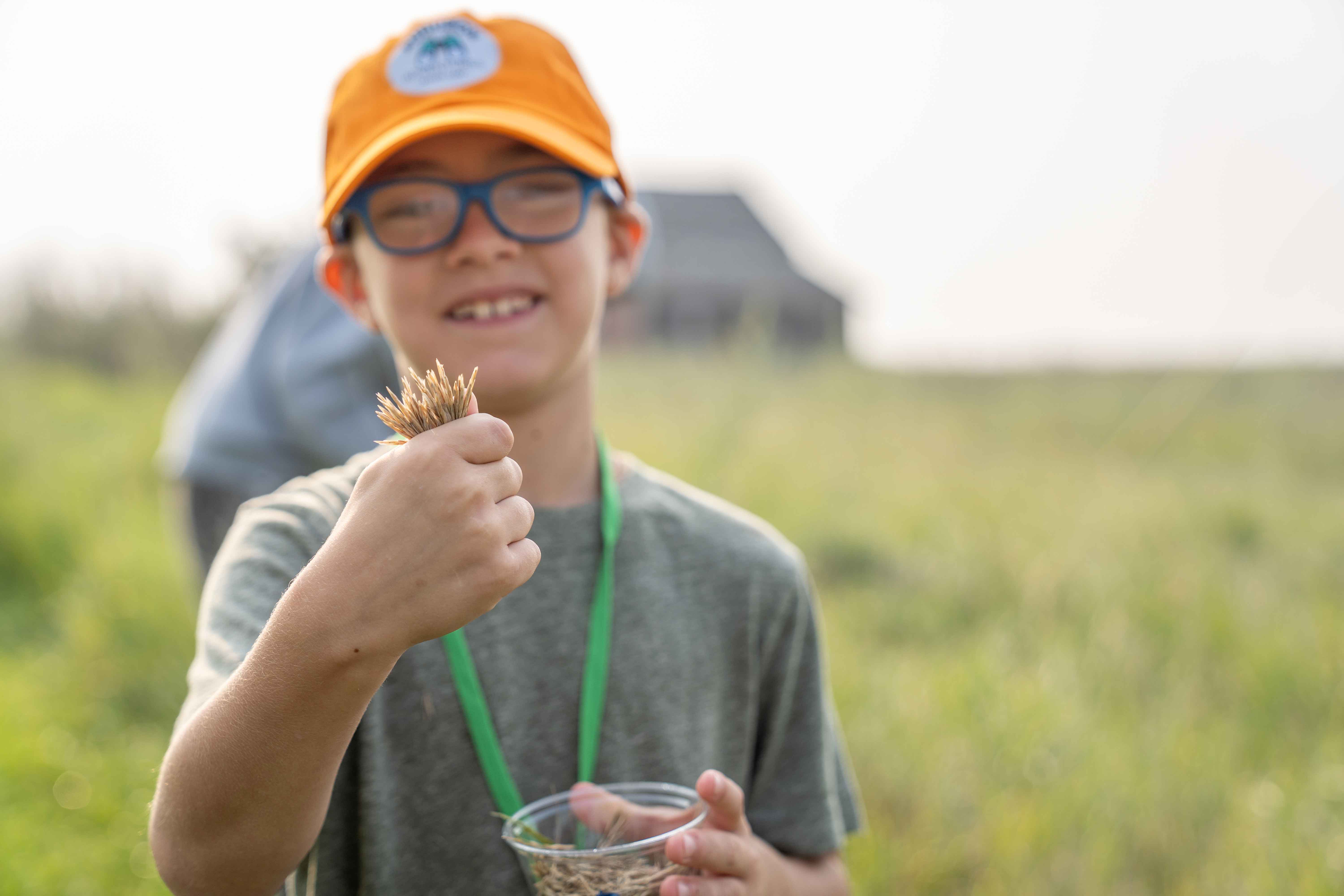 Child holding seeds harvested at camp.
