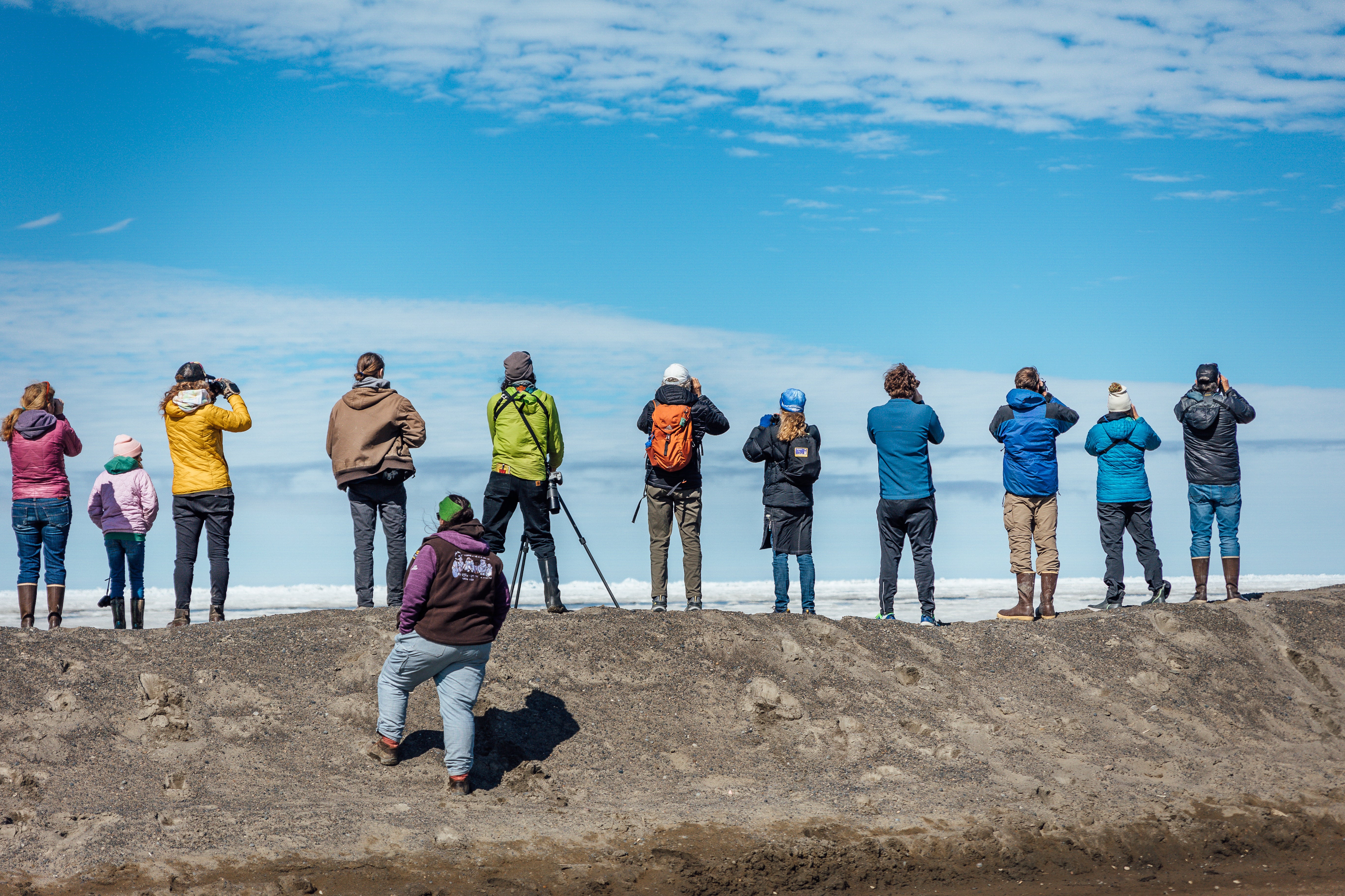 Multiple people lined up on coast with scopes
