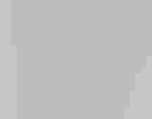 A young man wearing a uniform holds a broom on a boardwalk.