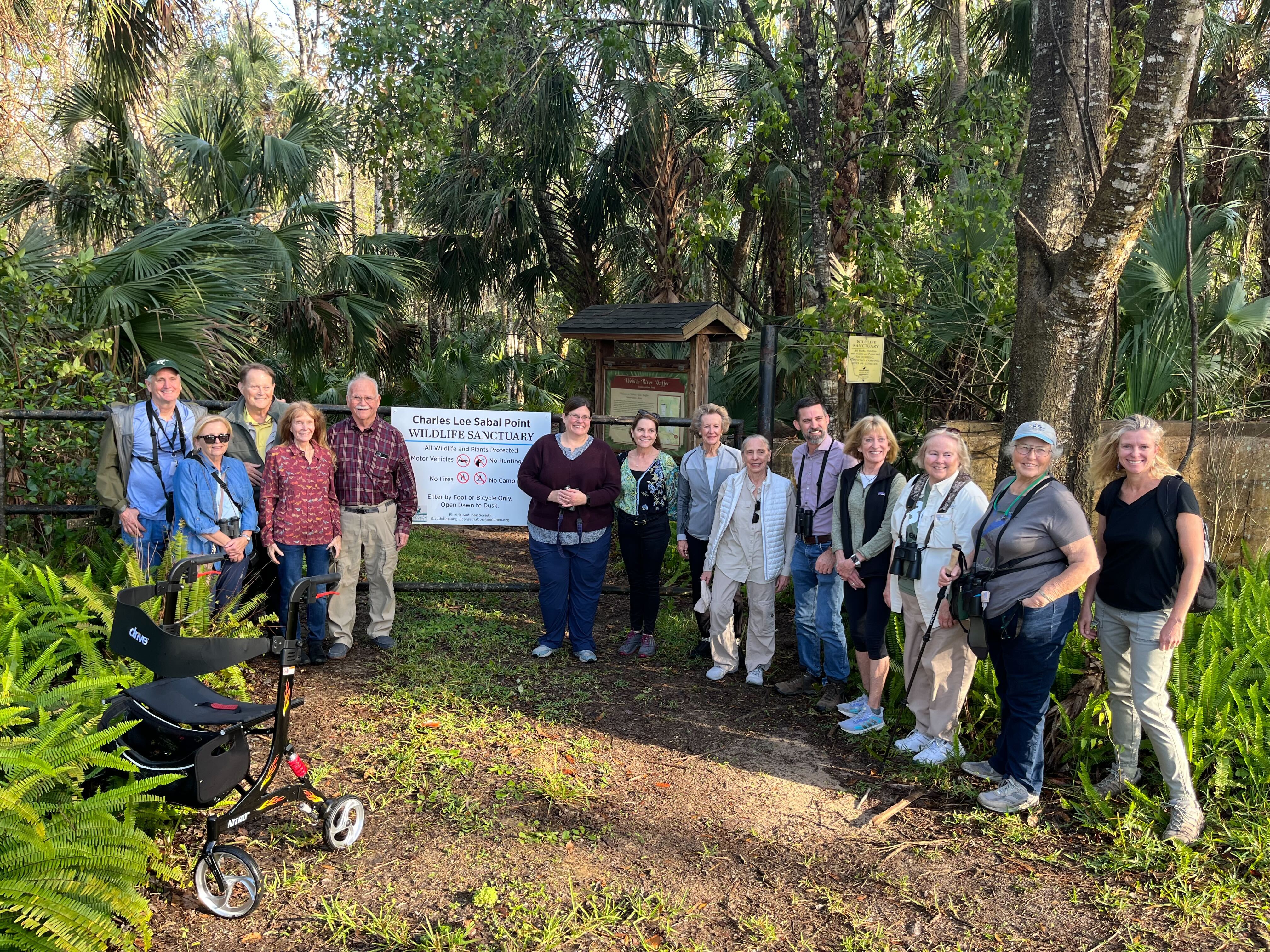 A group of people standing in front of a sign on a gate