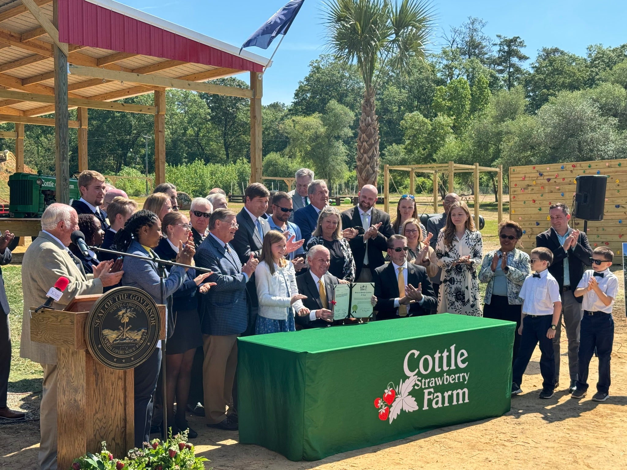 Stakeholders and legislators stand around a table where Governor McMaster is seated signing the working lands legislation
