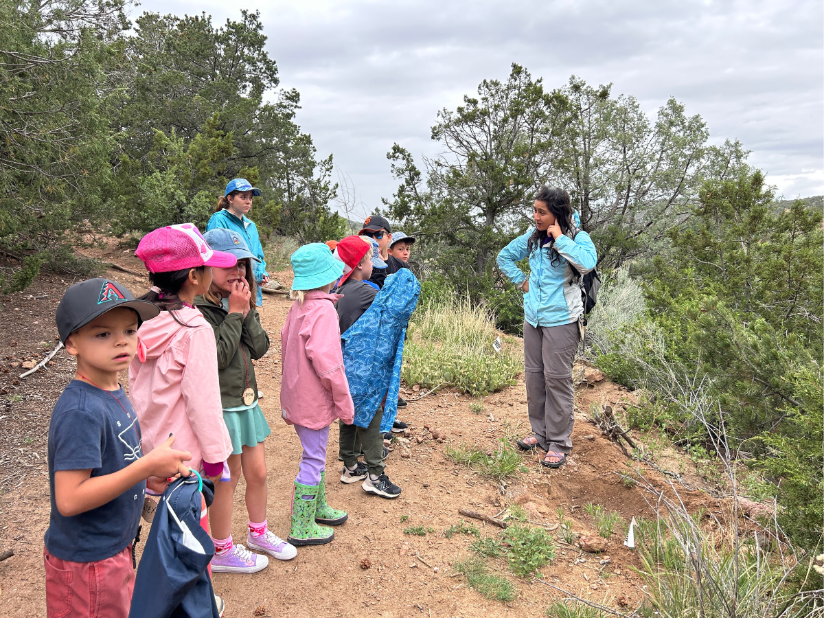 Educator Valerie Carollo leads campers in a listening observation game during a rainy-day hike.