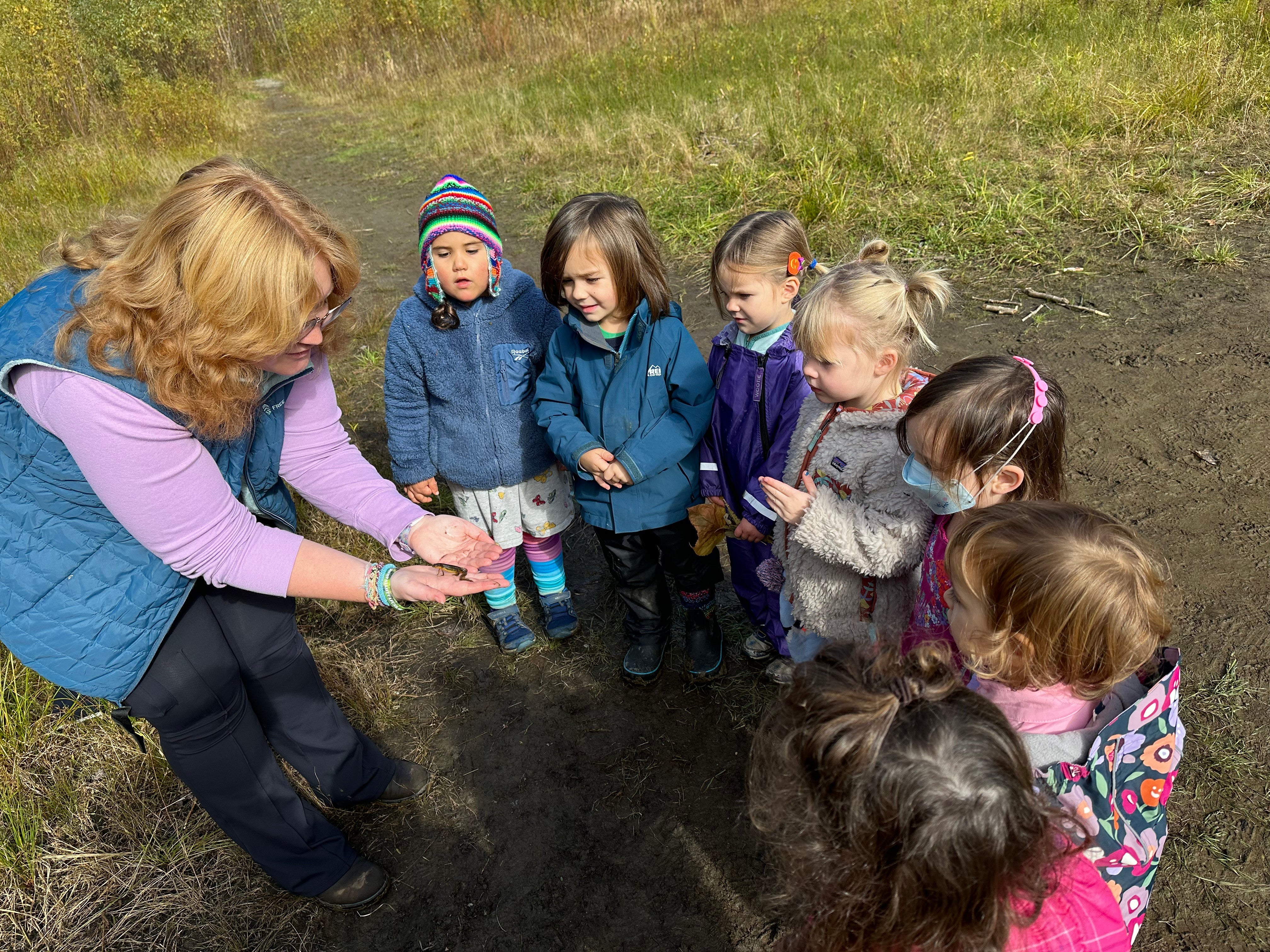an adult shows an eastern newt to a group of children