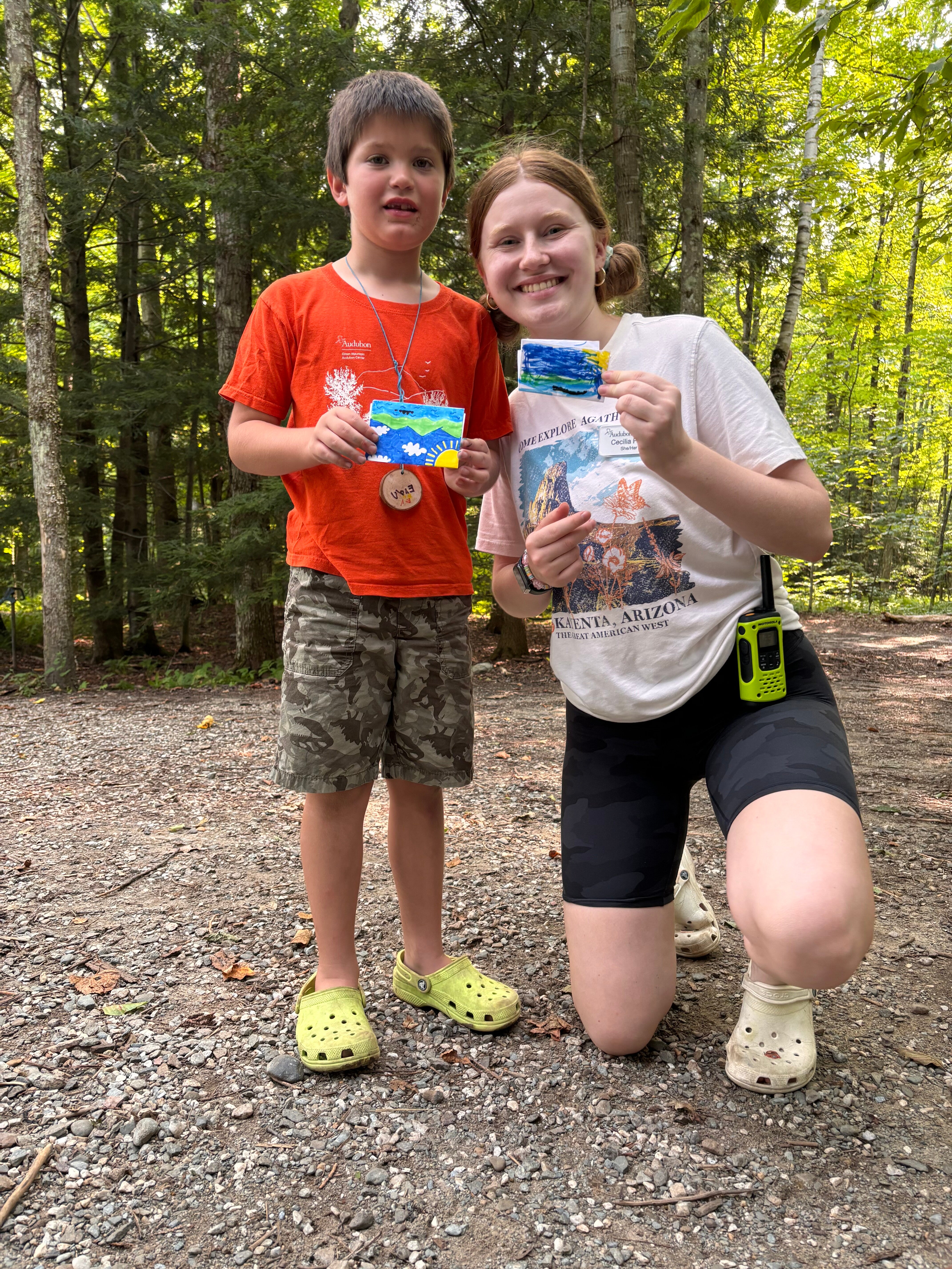 a child and an adult hold up small paintings