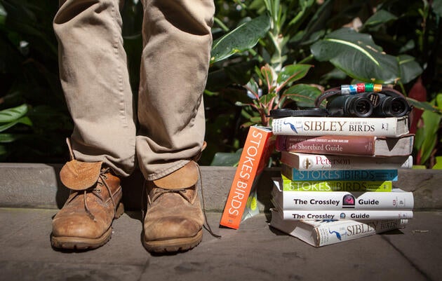 On the right a stack of bird guide seats on the ground, on the left a person wearing boots.