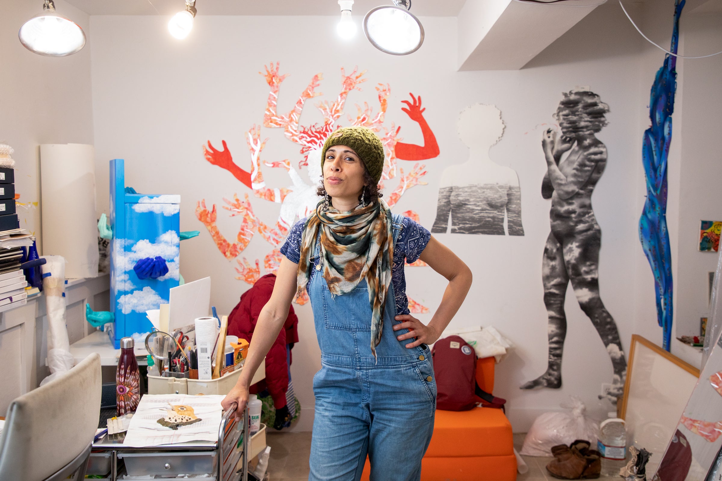 The artist leans for a portrait in her small studio filled with past work.