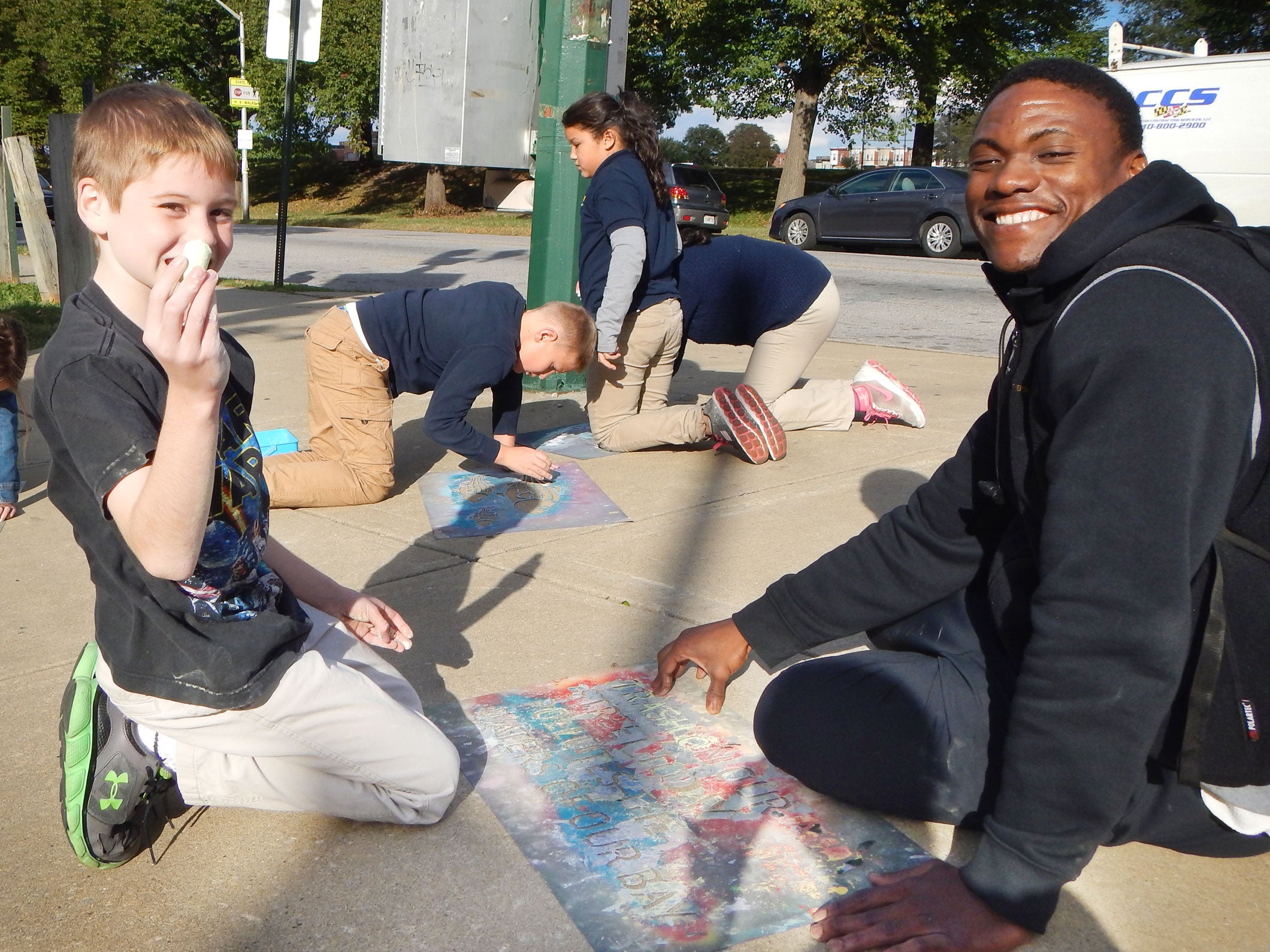 Mongar Pratt, right, helps a student chalk messages on a sidewalk. Courtesy of Patterson Park Audubon Center
