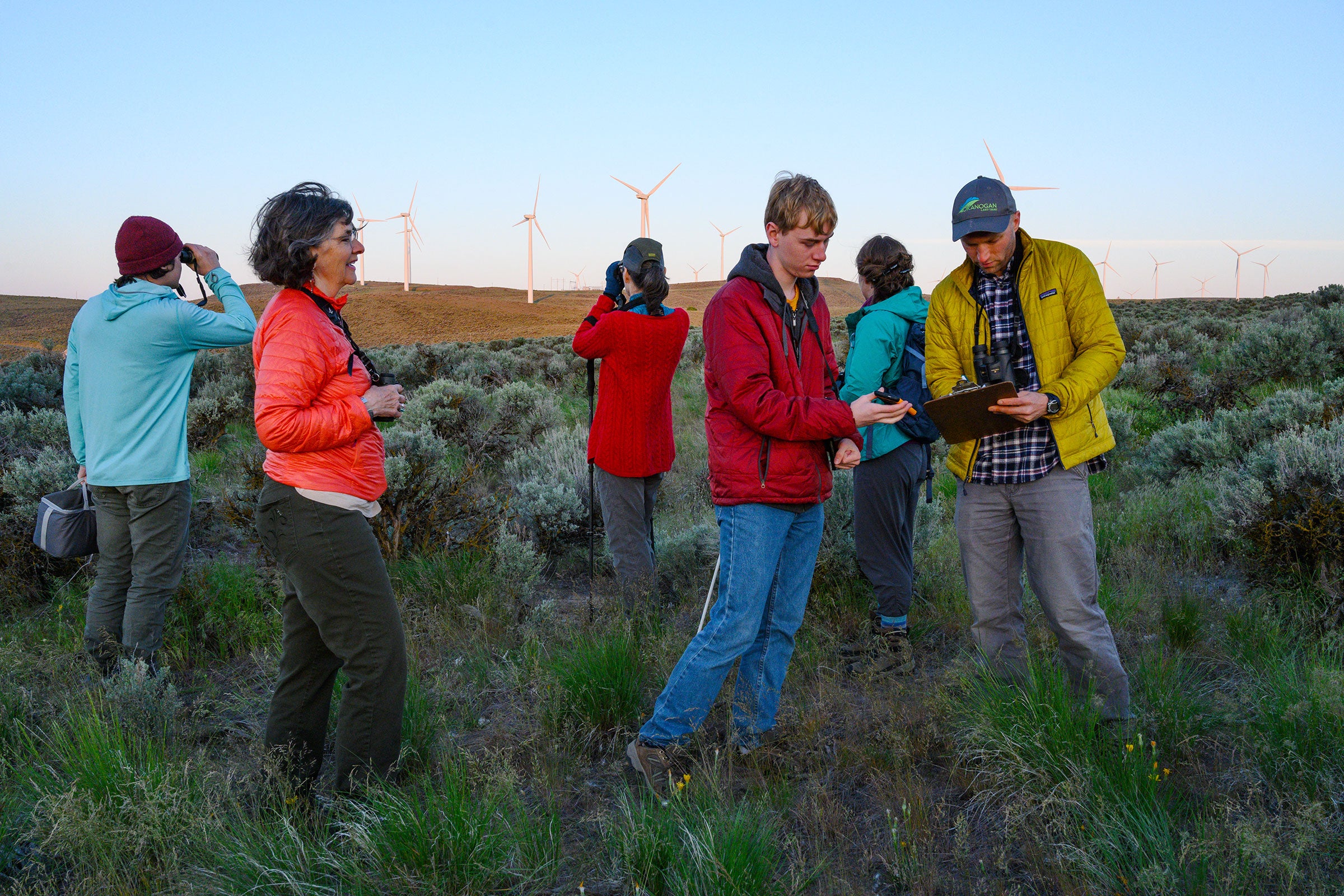 A Sagebrush Songbird Survey group hits the Wild Horse Wind and Solar Facility in Kittitas County, Washington, at first light. In front, Christi Norman observes as volunteers Curtis Mahon and John Rohrback record data. Dave Showalter